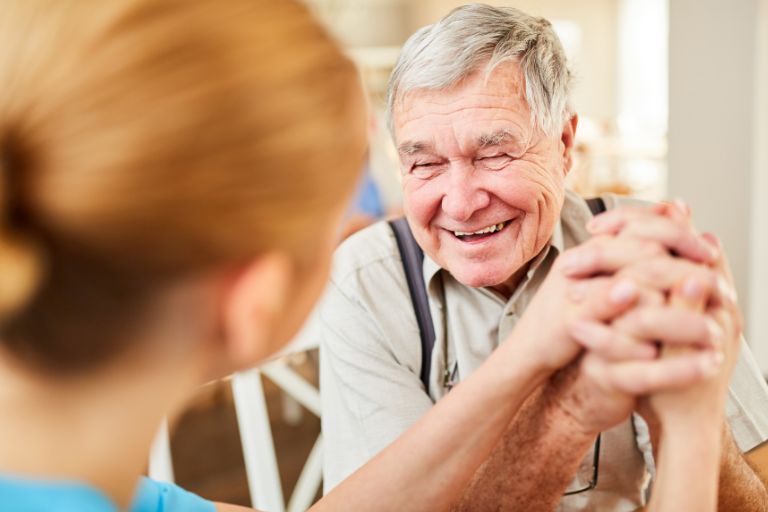 Older man laughing and holding hands with a younger woman