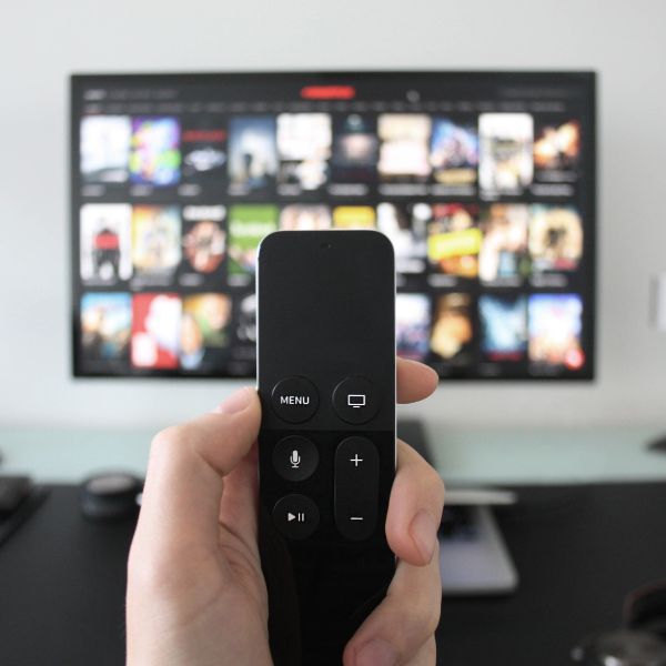 Person holding a TV remote in front of a TV screen