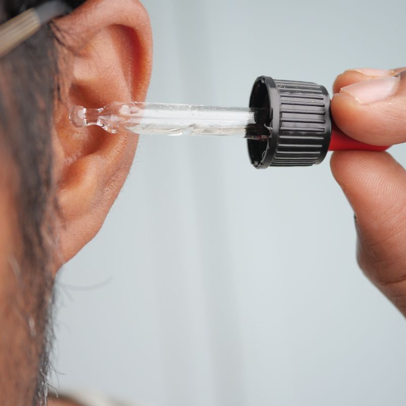 man applying ear drops in ear through pipette
