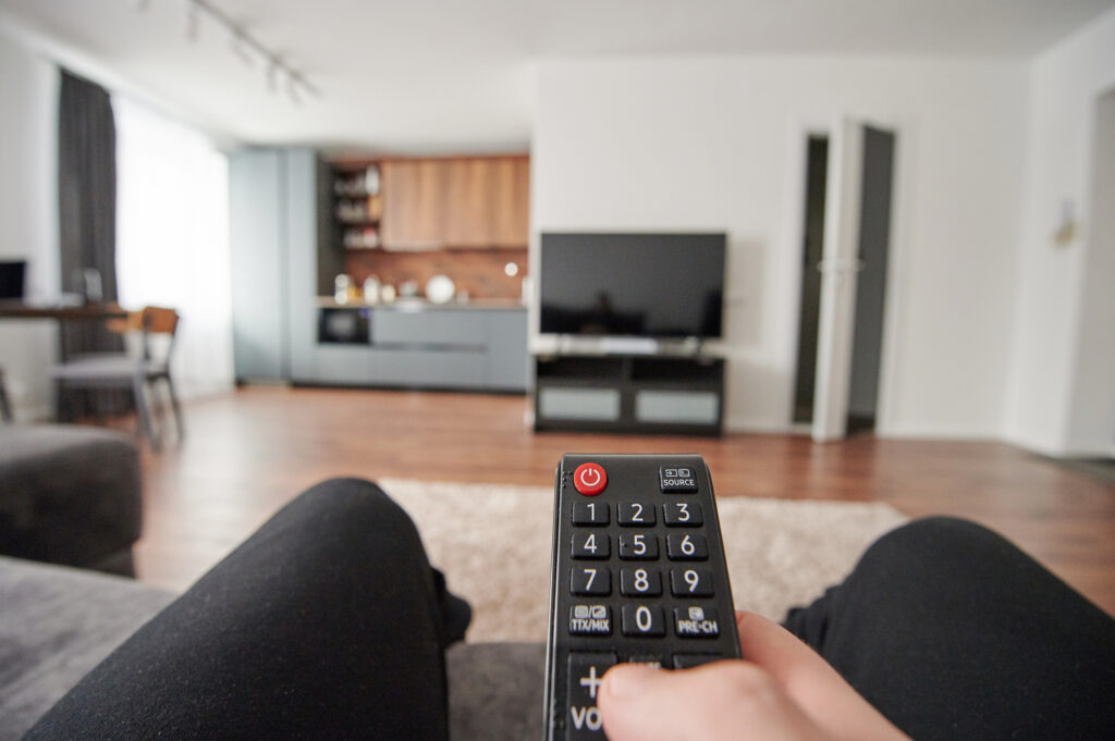 Person holding a remote control aimed at a TV