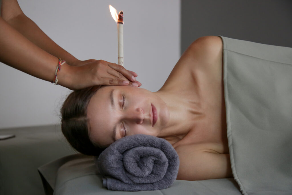 Woman receiving ear candle treatment at spa.